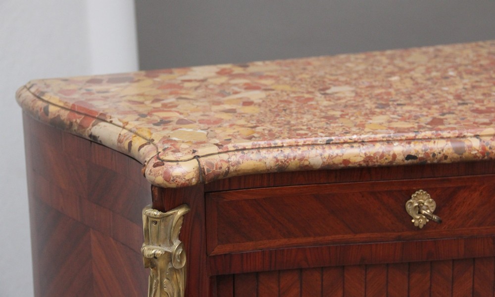 A pair of 19th-century French kingwood commodes featuring chevron parquetry veneer, mottled brown marble tops, and decorative gilt-bronze mounts. View X