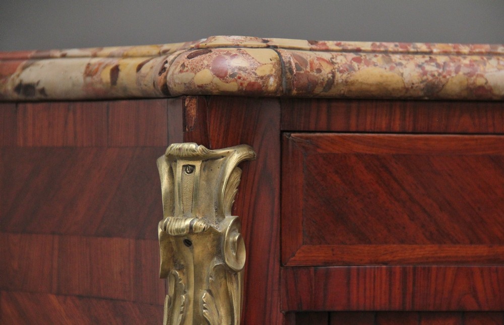 A pair of 19th-century French kingwood commodes featuring chevron parquetry veneer, mottled brown marble tops, and decorative gilt-bronze mounts. View XV