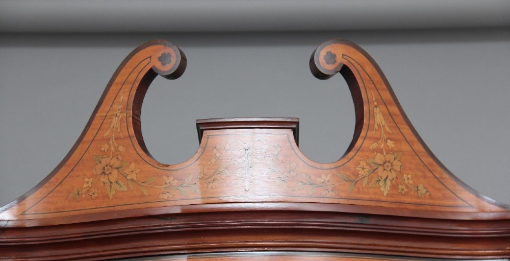 A 19th-century satinwood display cabinet featuring a swan-neck pediment, curved central glass door, and marquetry inlaid lower doors on square tapered legs. View VIII