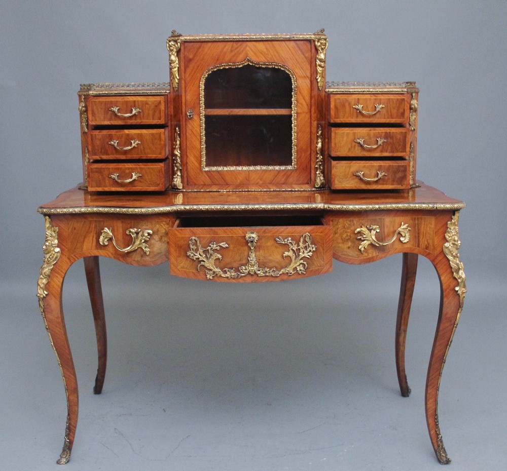 A 19th-century walnut writing desk featuring a raised superstructure with a central glazed cupboard flanked by small drawers, trimmed with gilt-bronze mounts on cabriole legs. View II