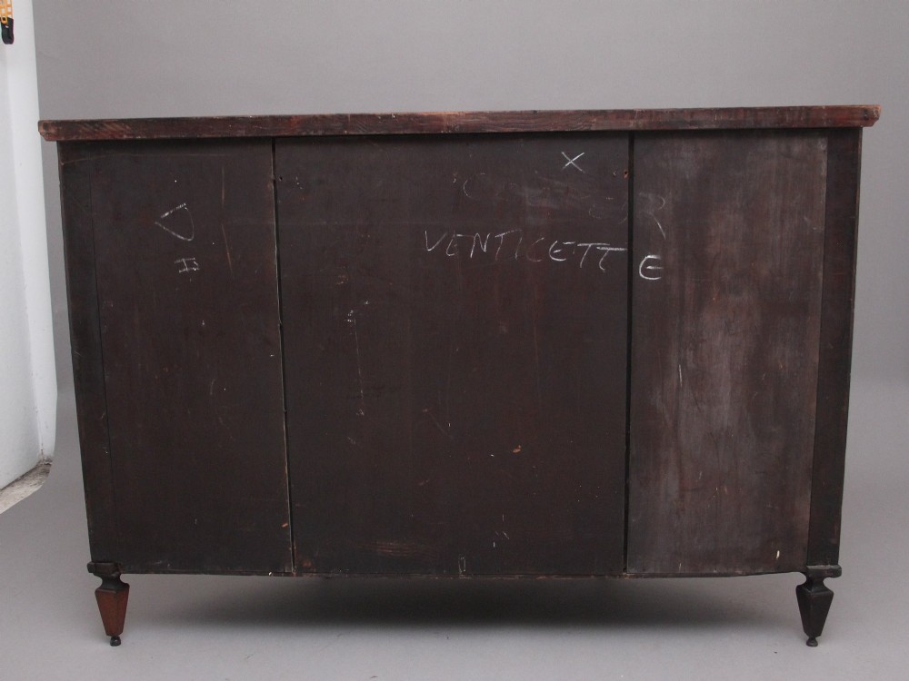 A 19th-century bow-fronted mahogany side cabinet featuring detailed satinwood marquetry panels with classical figures and swags on turned tapered legs. View VII