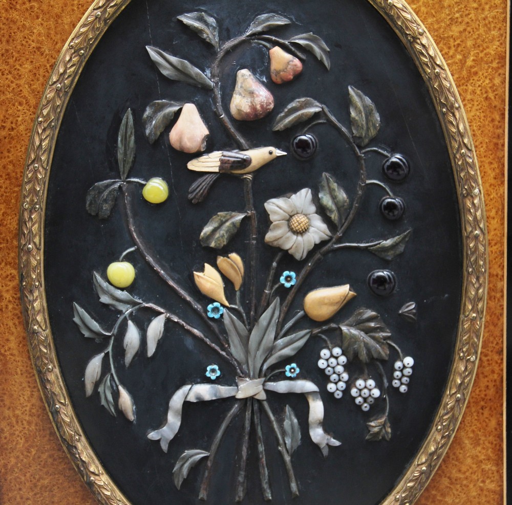 A 19th-century Victorian amboyna and ebonised credenza featuring curved glass side cabinets, gilt-metal mounts, porcelain plaque frieze details, and central oval panels inlaid with stone floral motifs. View X