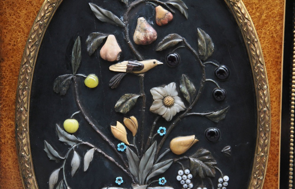 A 19th-century Victorian amboyna and ebonised credenza featuring curved glass side cabinets, gilt-metal mounts, porcelain plaque frieze details, and central oval panels inlaid with stone floral motifs. View XI