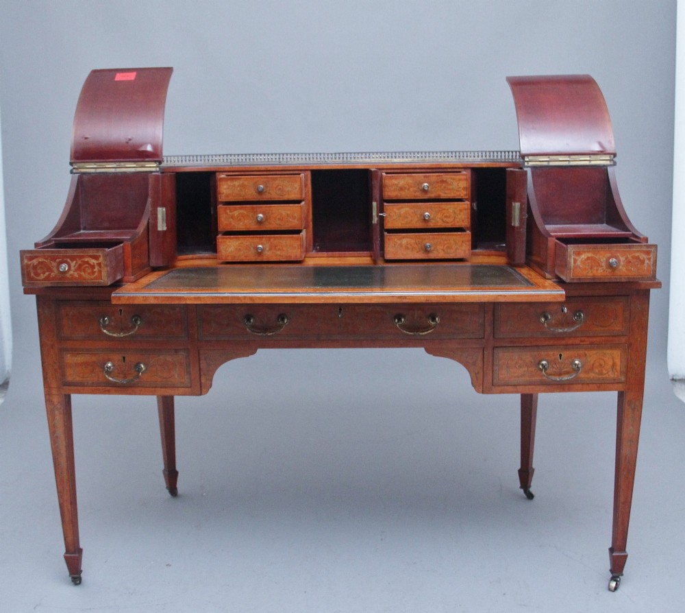 A 19th-century satinwood Carlton House desk featuring floral marquetry inlay, multiple small drawers, a central writing surface, a brass gallery rail, and square tapered legs on castors. View III