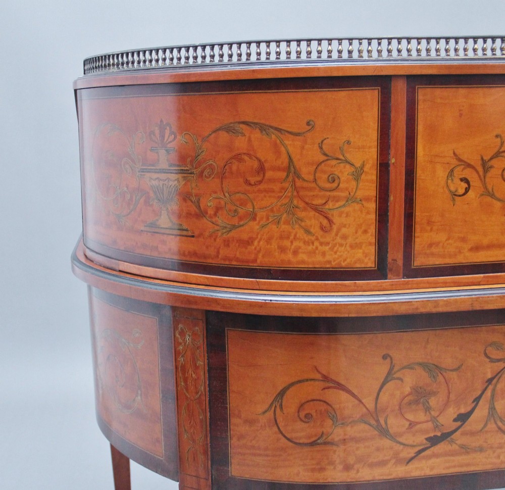 A 19th-century satinwood Carlton House desk featuring floral marquetry inlay, multiple small drawers, a central writing surface, a brass gallery rail, and square tapered legs on castors. View X