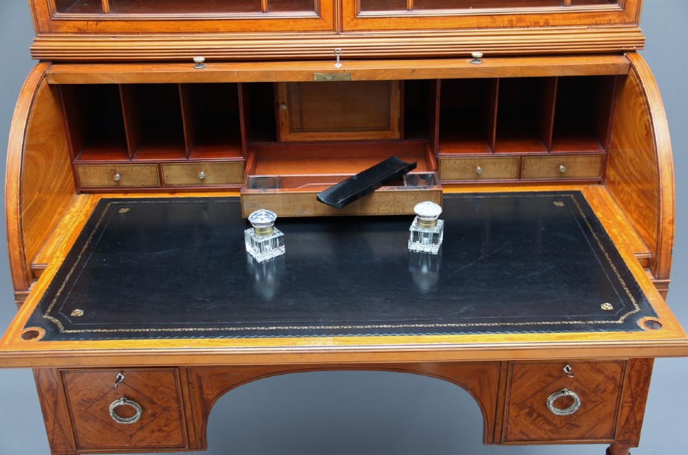 A 19th-century satinwood cylinder bureau bookcase featuring upper glazed doors, a roll-top writing section, lower drawers, and turned fluted legs. View V