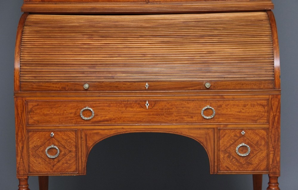 A 19th-century satinwood cylinder bureau bookcase featuring upper glazed doors, a roll-top writing section, lower drawers, and turned fluted legs. View IX