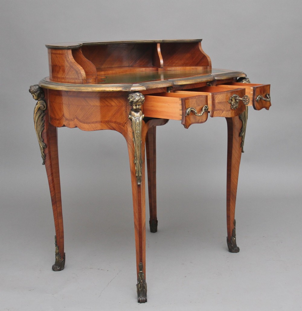 A 19th-century kingwood writing table featuring decorative gilt-bronze ormolu mounts, cabriole legs, a green leather writing surface, and a raised superstructure with pigeonholes. View II