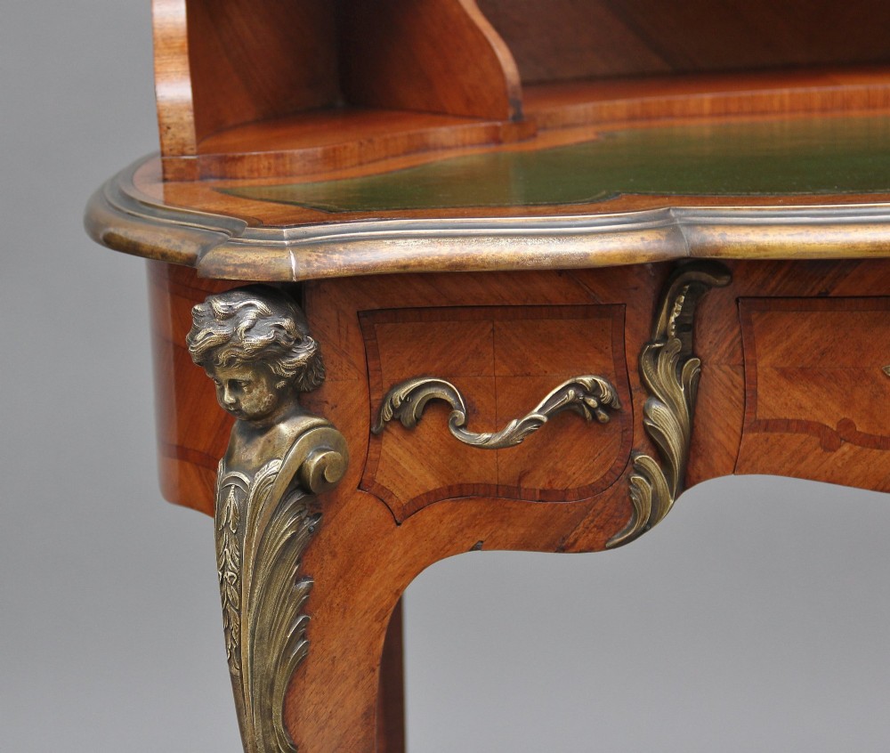 A 19th-century kingwood writing table featuring decorative gilt-bronze ormolu mounts, cabriole legs, a green leather writing surface, and a raised superstructure with pigeonholes. View XIII