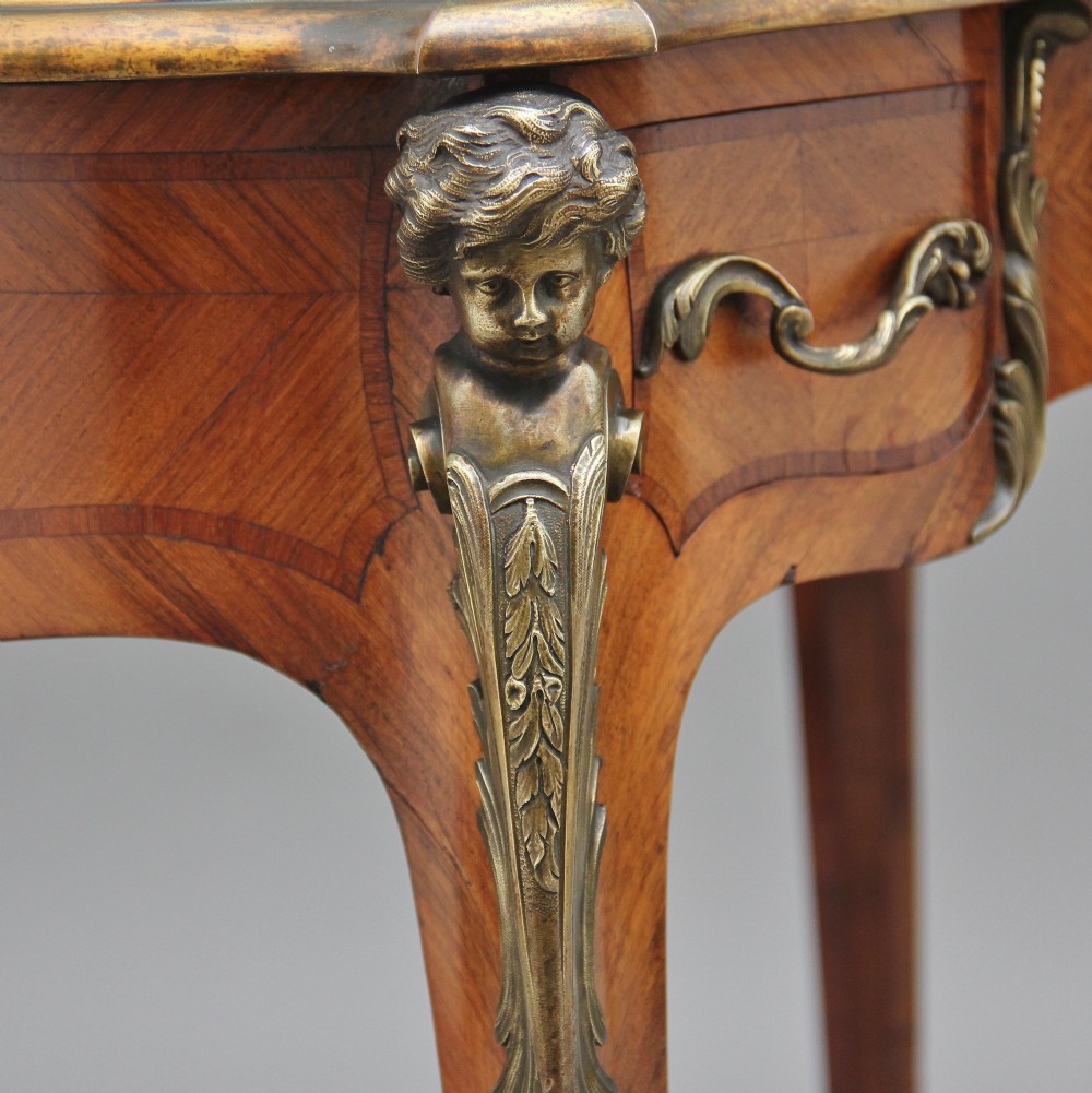 A 19th-century kingwood writing table featuring decorative gilt-bronze ormolu mounts, cabriole legs, a green leather writing surface, and a raised superstructure with pigeonholes. View XV