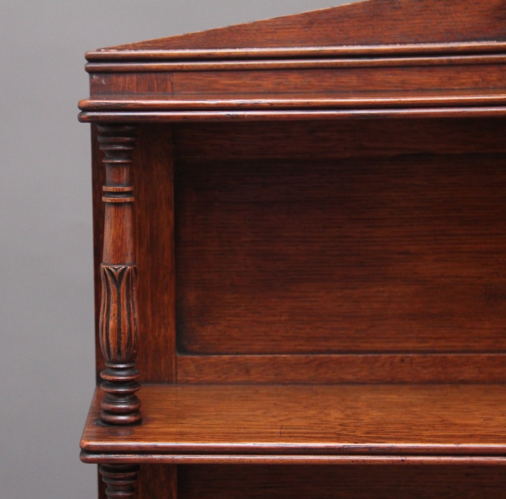 An early nineteenth-century oak bookcase featuring three open upper shelves, a pediment top, and a lower cabinet with a brass wire mesh door flanked by rope-twist columns. View VIII