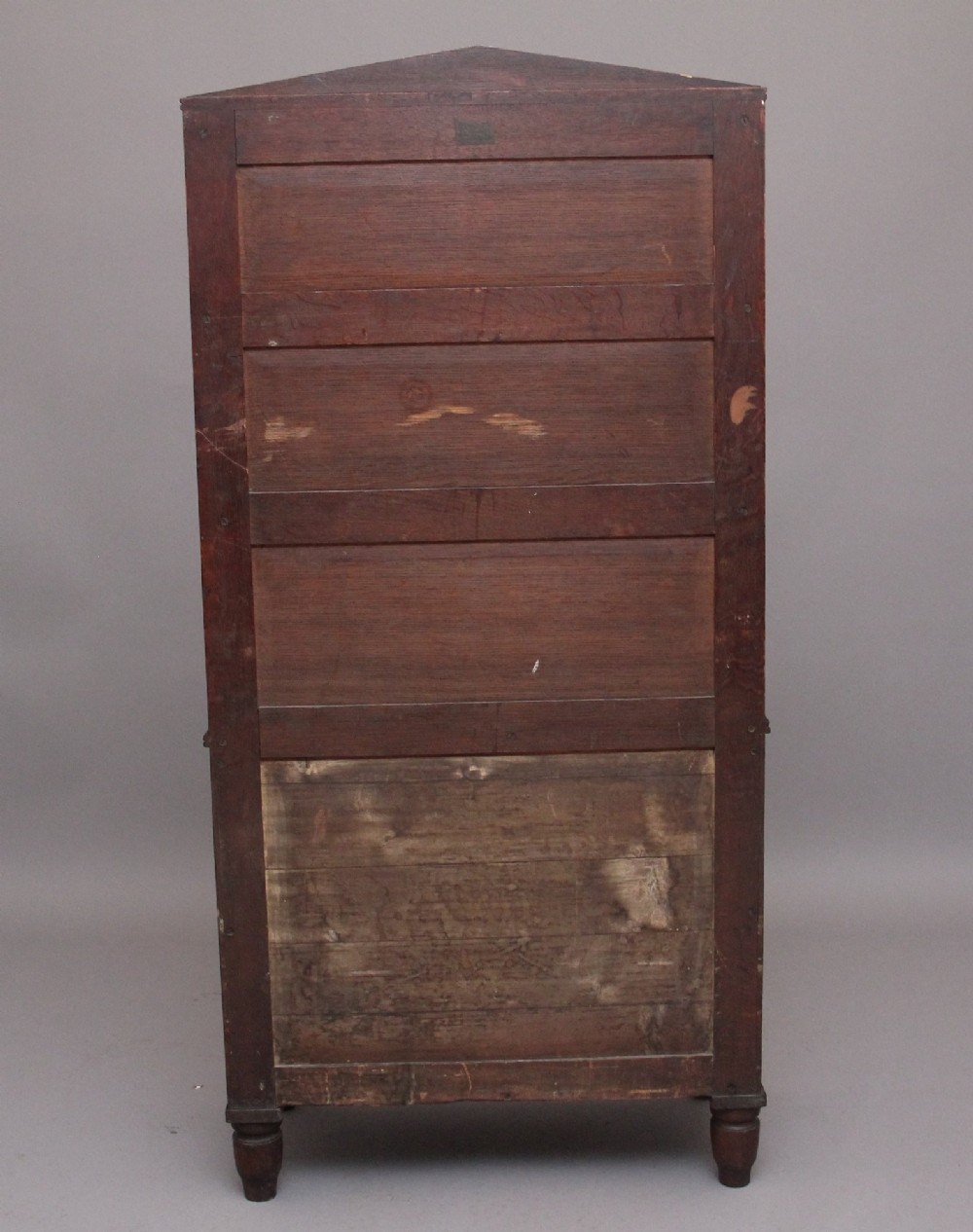An early nineteenth-century oak bookcase featuring three open upper shelves, a pediment top, and a lower cabinet with a brass wire mesh door flanked by rope-twist columns. View X