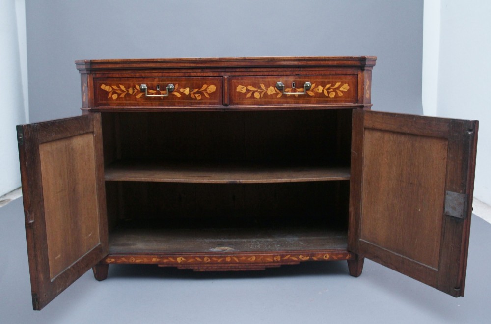 An early 19th-century Dutch mahogany travelling cabinet with intricate floral marquetry inlay, twin drawers over a two-door cupboard, and metal side carrying handles. View IV