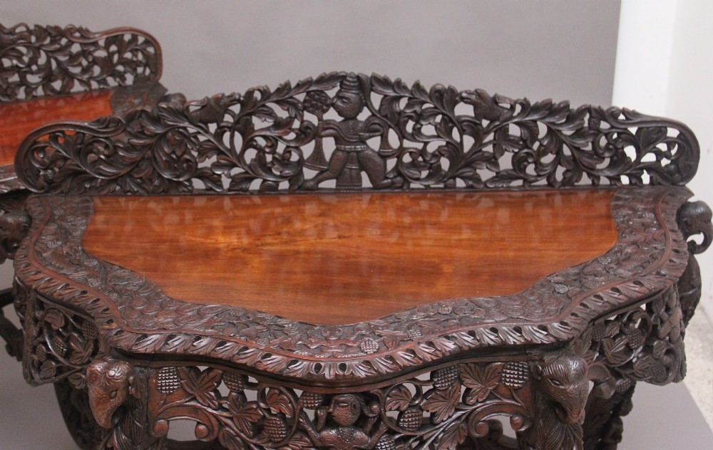 A pair of 19th-century dark wood console tables featuring intricate openwork carving, gallery backs, curved legs, and polished timber tops. View VI