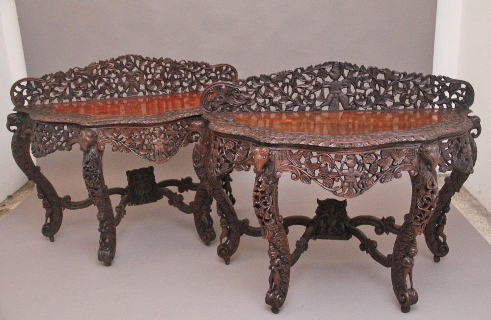 A pair of 19th-century dark wood console tables featuring intricate openwork carving, gallery backs, curved legs, and polished timber tops. View IX