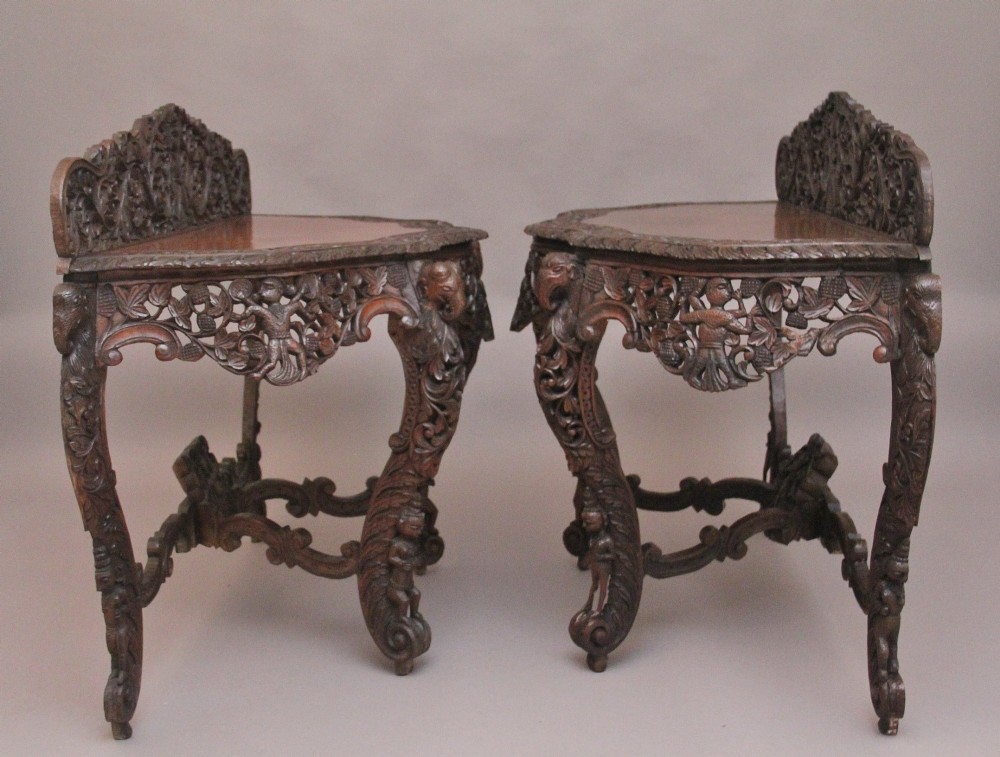 A pair of 19th-century dark wood console tables featuring intricate openwork carving, gallery backs, curved legs, and polished timber tops. View XII