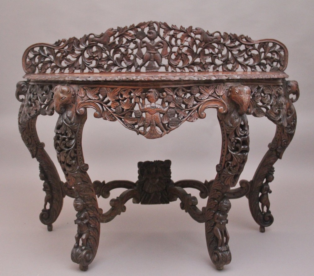 A pair of 19th-century dark wood console tables featuring intricate openwork carving, gallery backs, curved legs, and polished timber tops. View XV