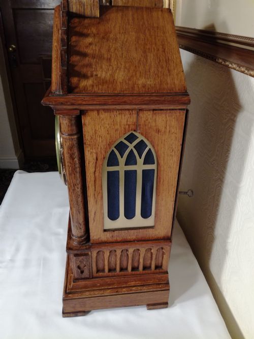 fig 1. A Victorian Gothic Revival carved oak bracket clock featuring a cathedral arch pediment with spire, blind tracery carving, corner columns, and a silvered dial with Roman numerals.