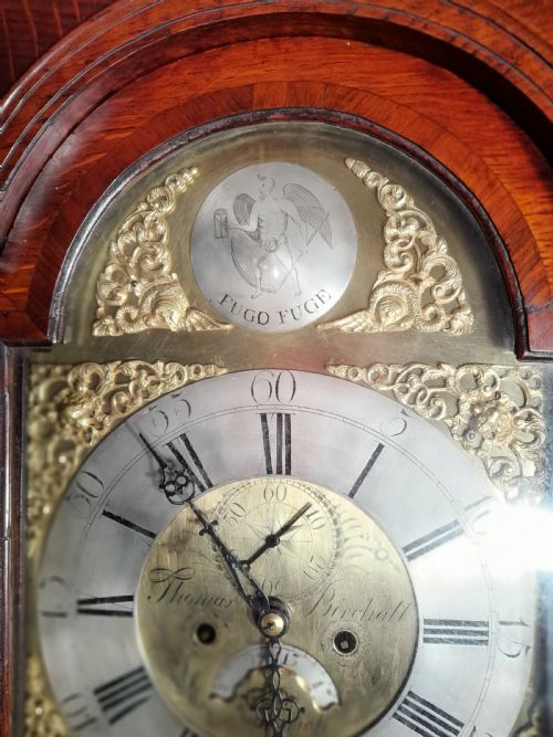 fig 2. A Georgian mahogany longcase clock featuring a swan-neck pediment with a brass eagle finial and an engraved brass dial.