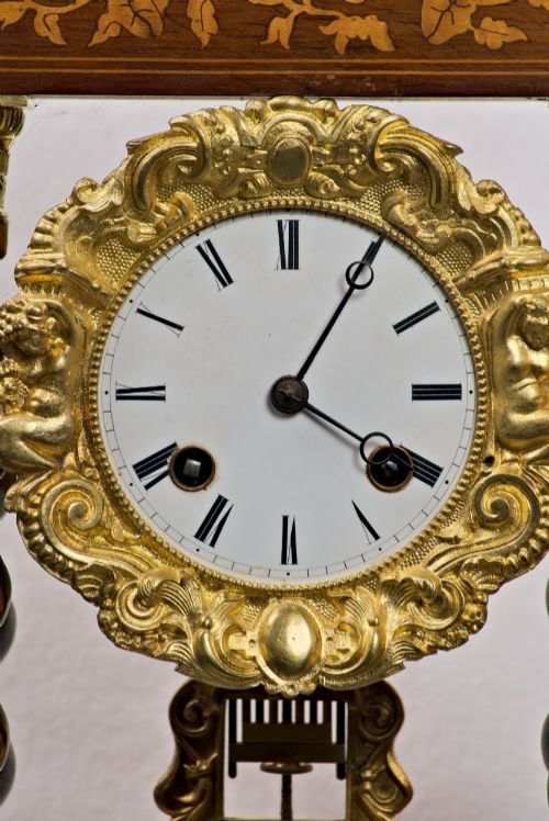 fig 2. A 19th-century rosewood portico clock featuring floral marquetry inlays, twin barley-twist columns with gilt capitals, and a white enamel dial with an ornate gilt bezel.