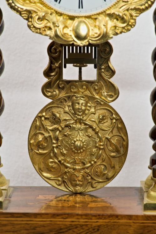 fig 3. A 19th-century rosewood portico clock featuring floral marquetry inlays, twin barley-twist columns with gilt capitals, and a white enamel dial with an ornate gilt bezel.