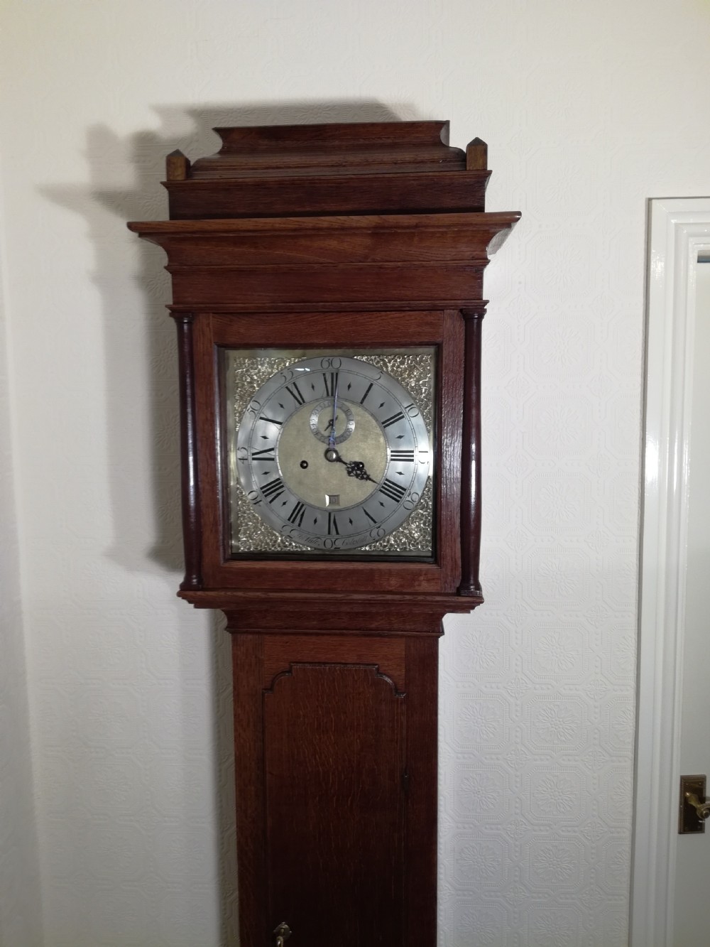 An 18th-century Georgian dark oak longcase clock featuring a square brass dial with decorative corner spandrels and a moulded hood. View VII