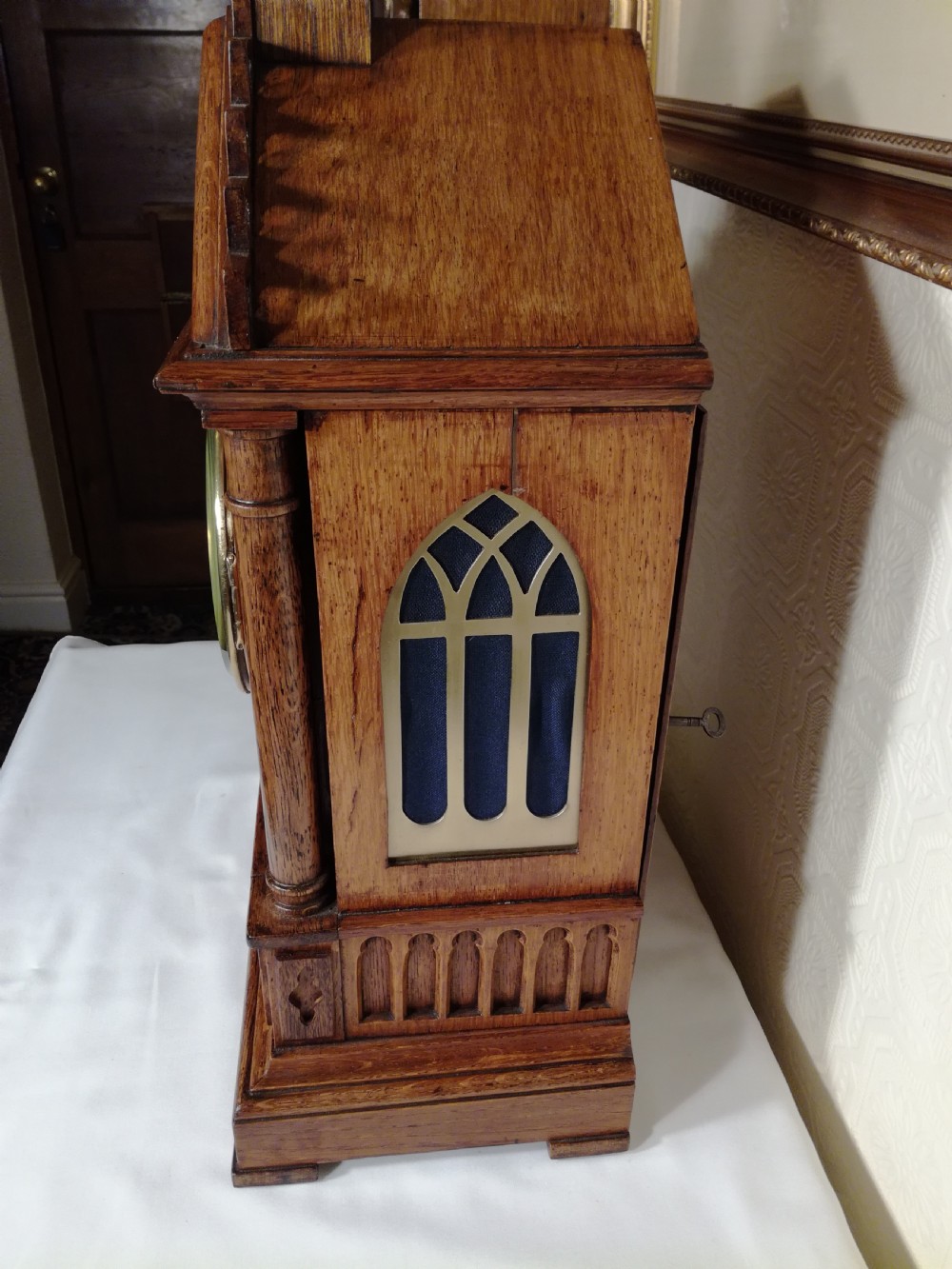 A Victorian Gothic Revival carved oak bracket clock featuring a cathedral arch pediment with spire, blind tracery carving, corner columns, and a silvered dial with Roman numerals. View II