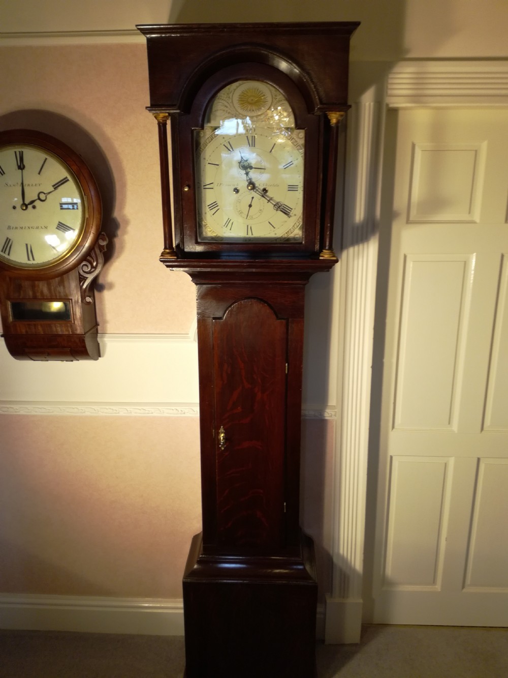 A Georgian dark mahogany longcase clock featuring an arched dial hood with turned columns and a tall waist door.