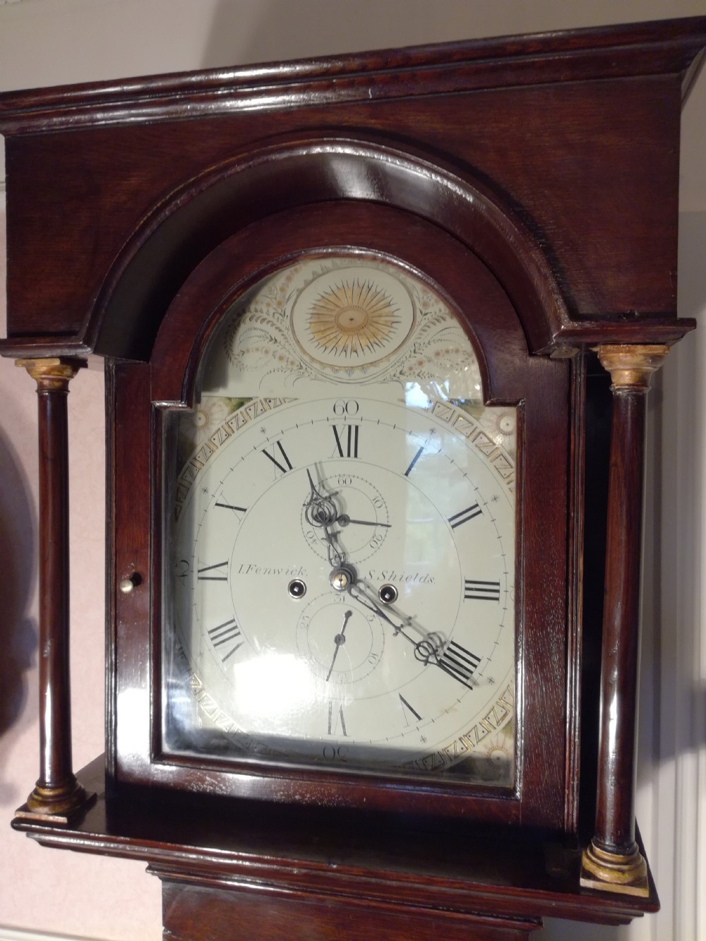 A Georgian dark mahogany longcase clock featuring an arched dial hood with turned columns and a tall waist door. View II