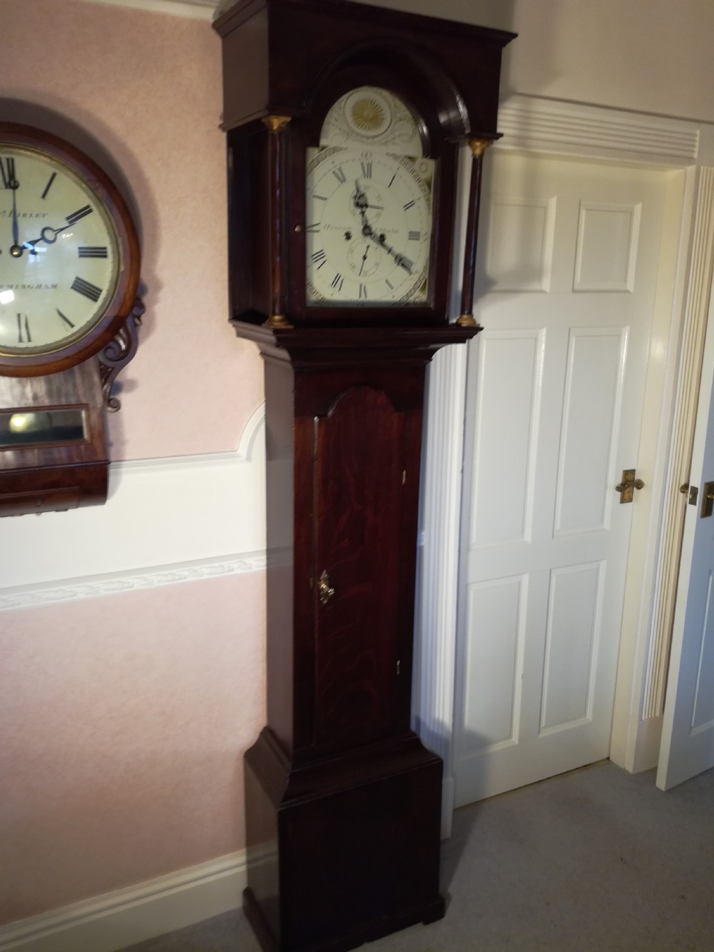 A Georgian dark mahogany longcase clock featuring an arched dial hood with turned columns and a tall waist door. View V