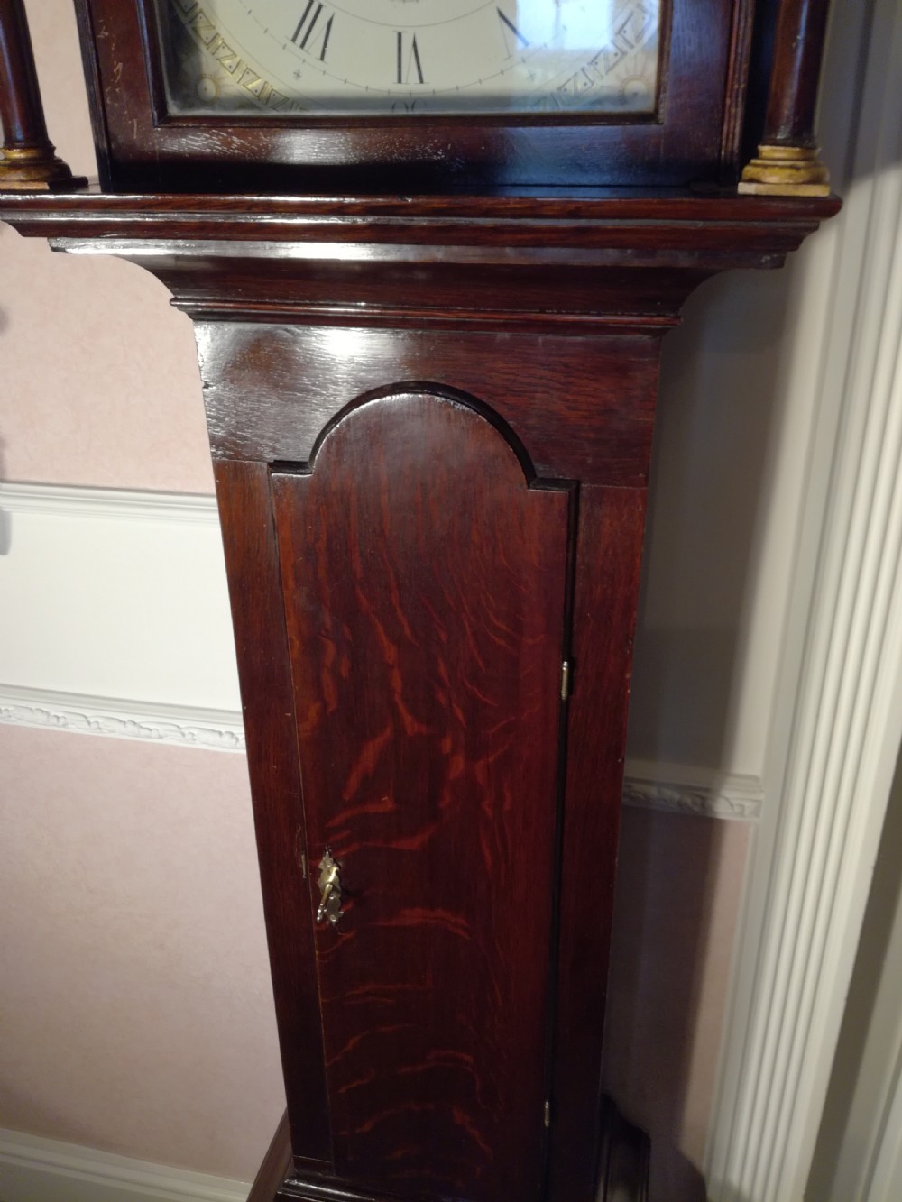 A Georgian dark mahogany longcase clock featuring an arched dial hood with turned columns and a tall waist door. View VI
