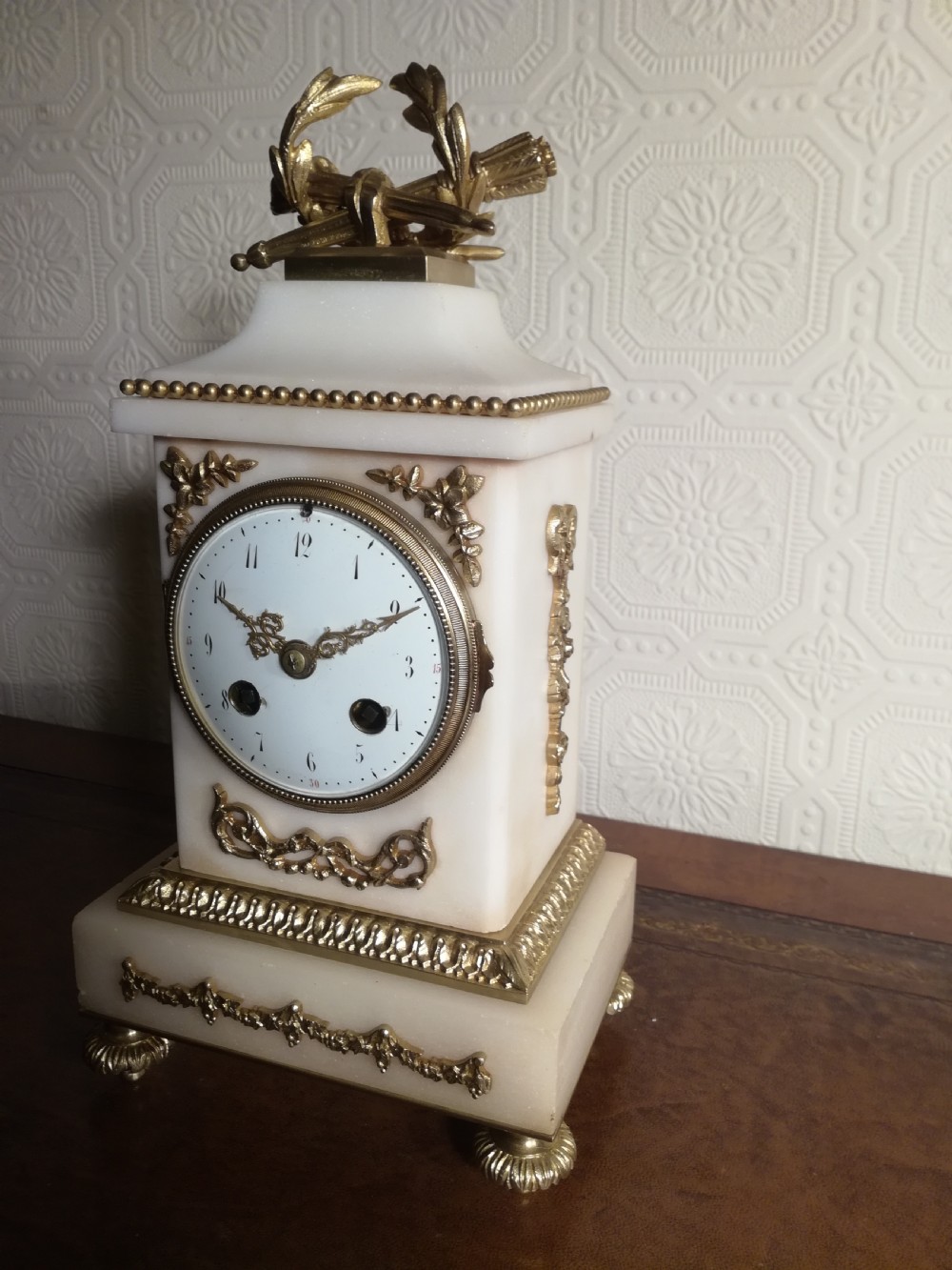 A French Louis XVI style white marble mantel clock featuring gilt bronze mounts, a laurel wreath finial, and an enamel dial. View III