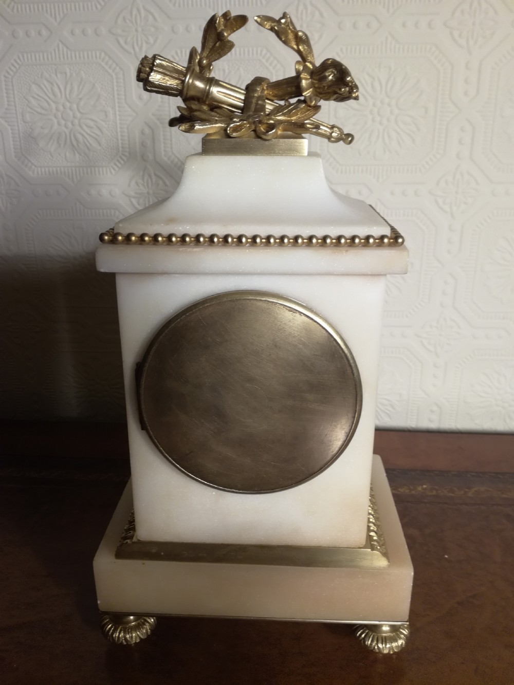 A French Louis XVI style white marble mantel clock featuring gilt bronze mounts, a laurel wreath finial, and an enamel dial. View VI