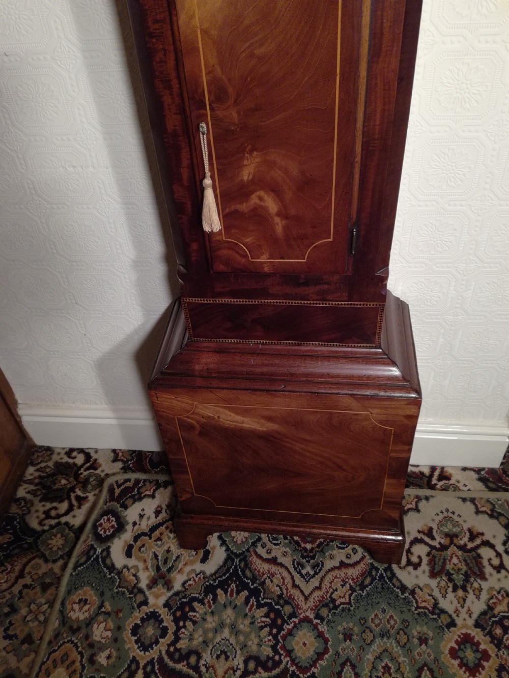 A tall Regency flame mahogany longcase clock featuring brass ball finials, spiral twisted columns flanking the hood, and an arched painted dial with Roman numerals. View VI