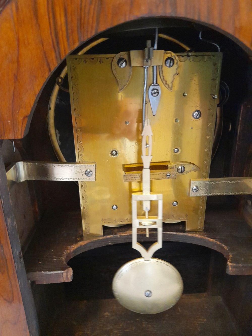 A Regency period rosewood bracket clock featuring geometric brass inlay, arched top with brass handle, gothic side frets, circular dial, and brass ball feet. View XI