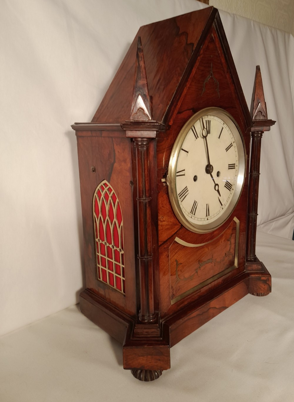 An antique Gothic Revival rosewood bracket clock with pointed arch pinnacles, brass foliate inlay, and a circular white dial with Roman numerals. View III