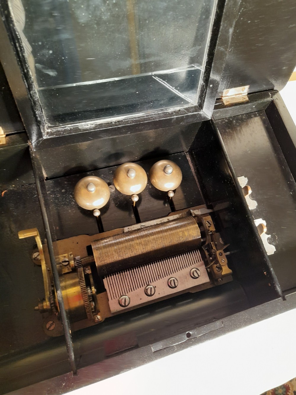 An antique wooden music box with an ebonised lower case, a mahogany hinged lid featuring a marquetry urn inlay, and a central keyhole. View VII