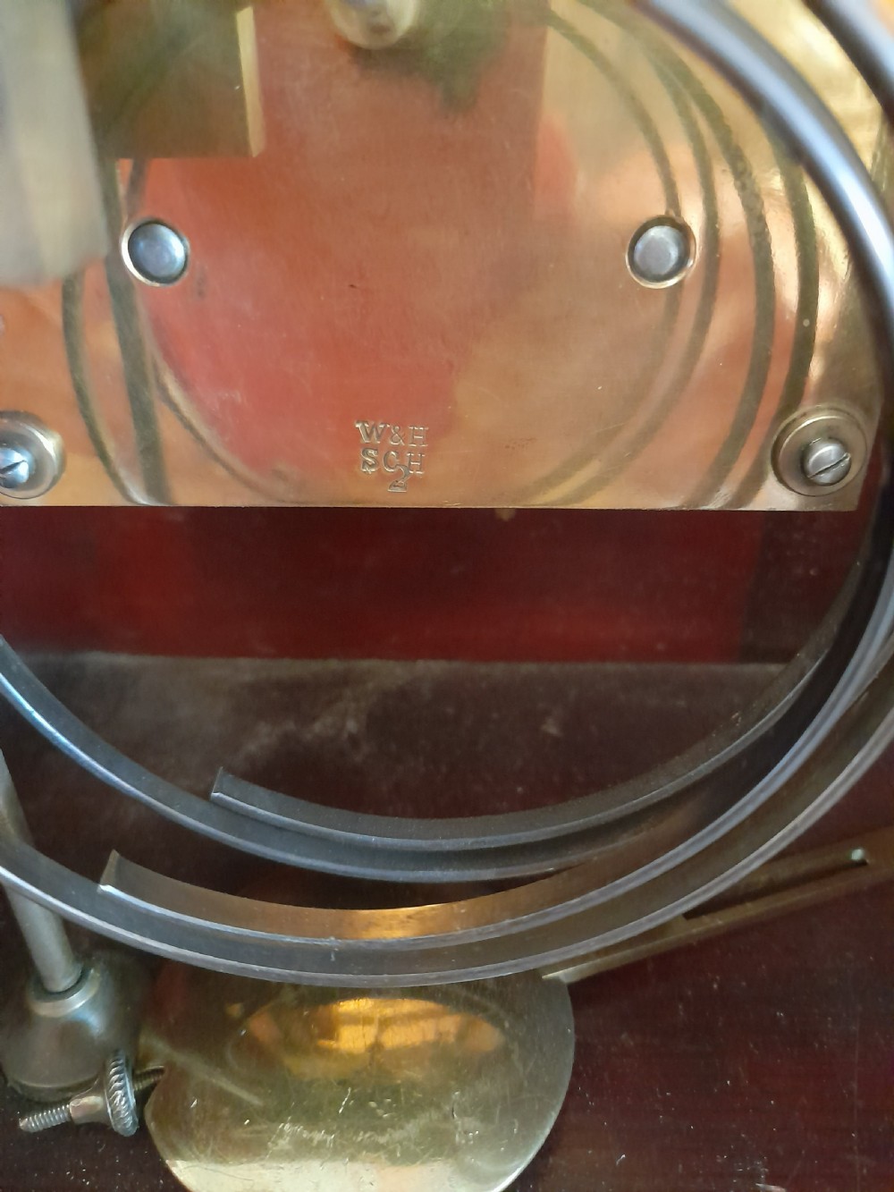 An arched mahogany wooden bracket clock with a silvered brass dial displaying Roman numerals and a small regulating dial at the top. View VIII