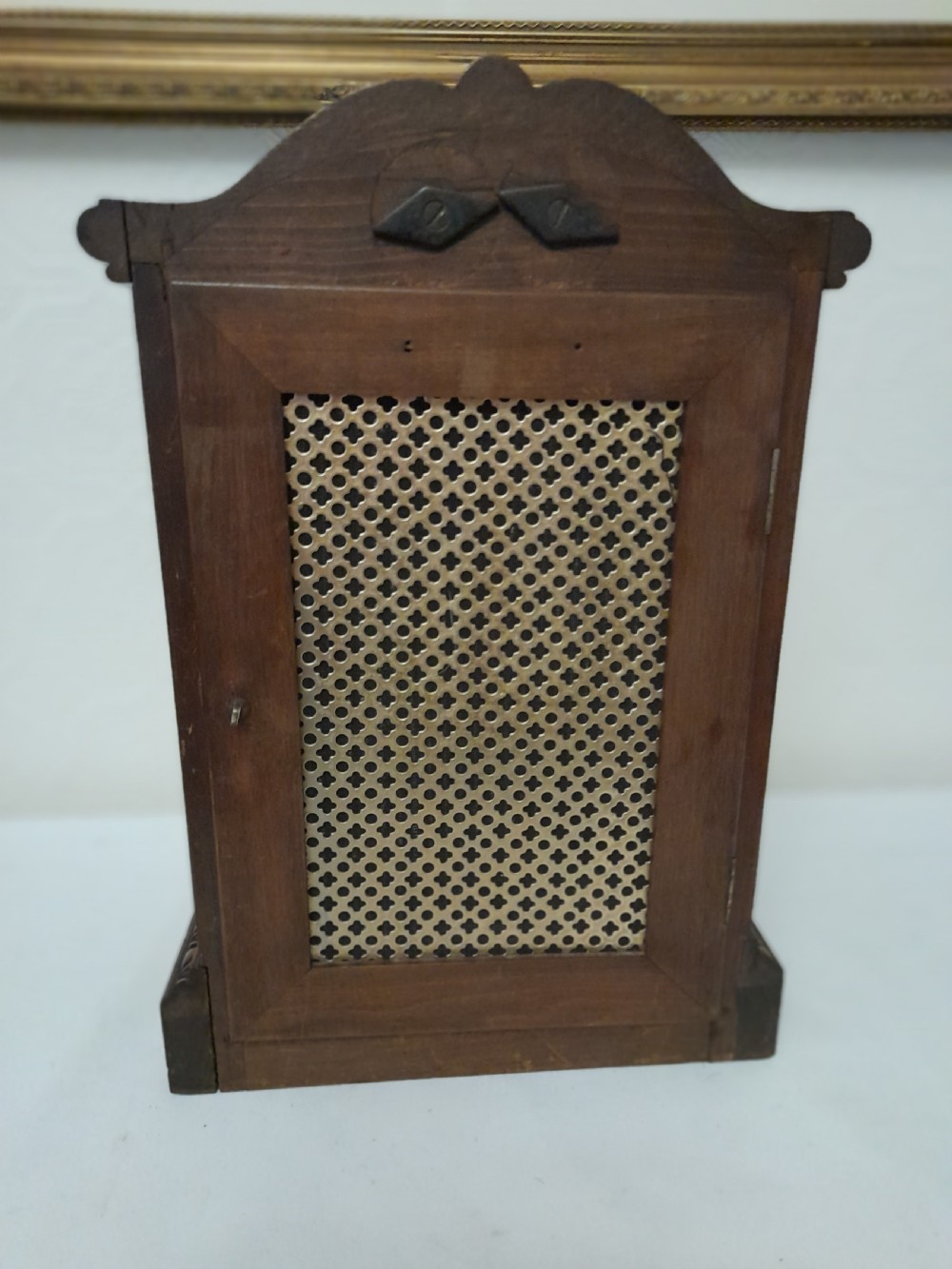 An Edwardian carved oak bracket clock featuring a silvered dial, brass bezel, arch top scroll moulding, and Westminster chime regulation sub-dials. View VII