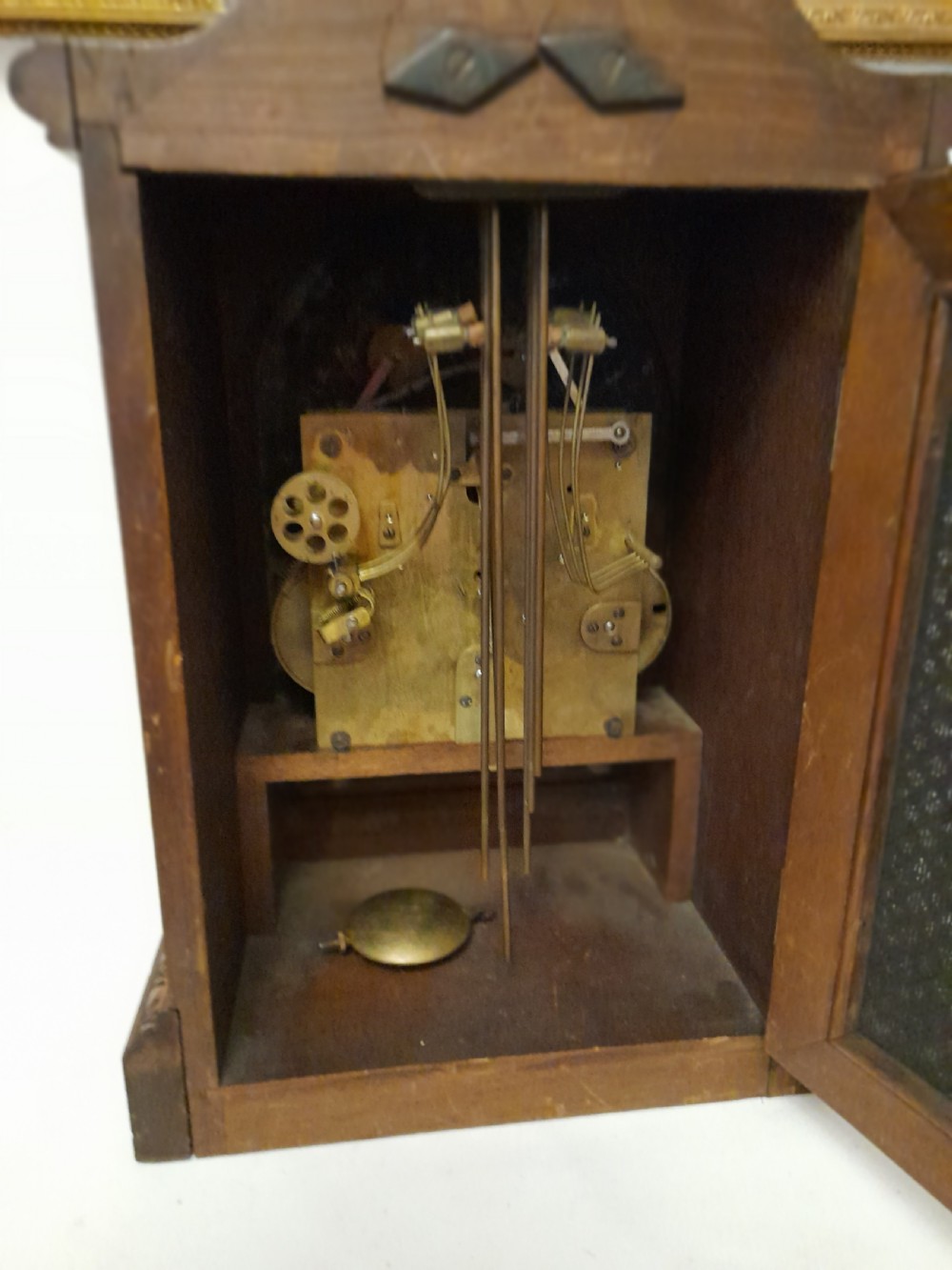 An Edwardian carved oak bracket clock featuring a silvered dial, brass bezel, arch top scroll moulding, and Westminster chime regulation sub-dials. View VIII