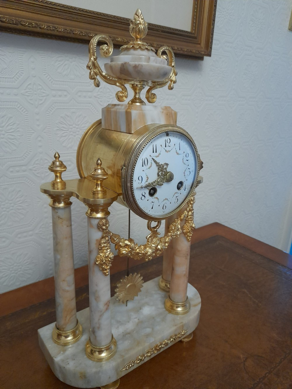 A French Louis XVI style marble and gilt brass portico mantel clock featuring four columns, floral swags, an urn finial, and an enamel dial. View II