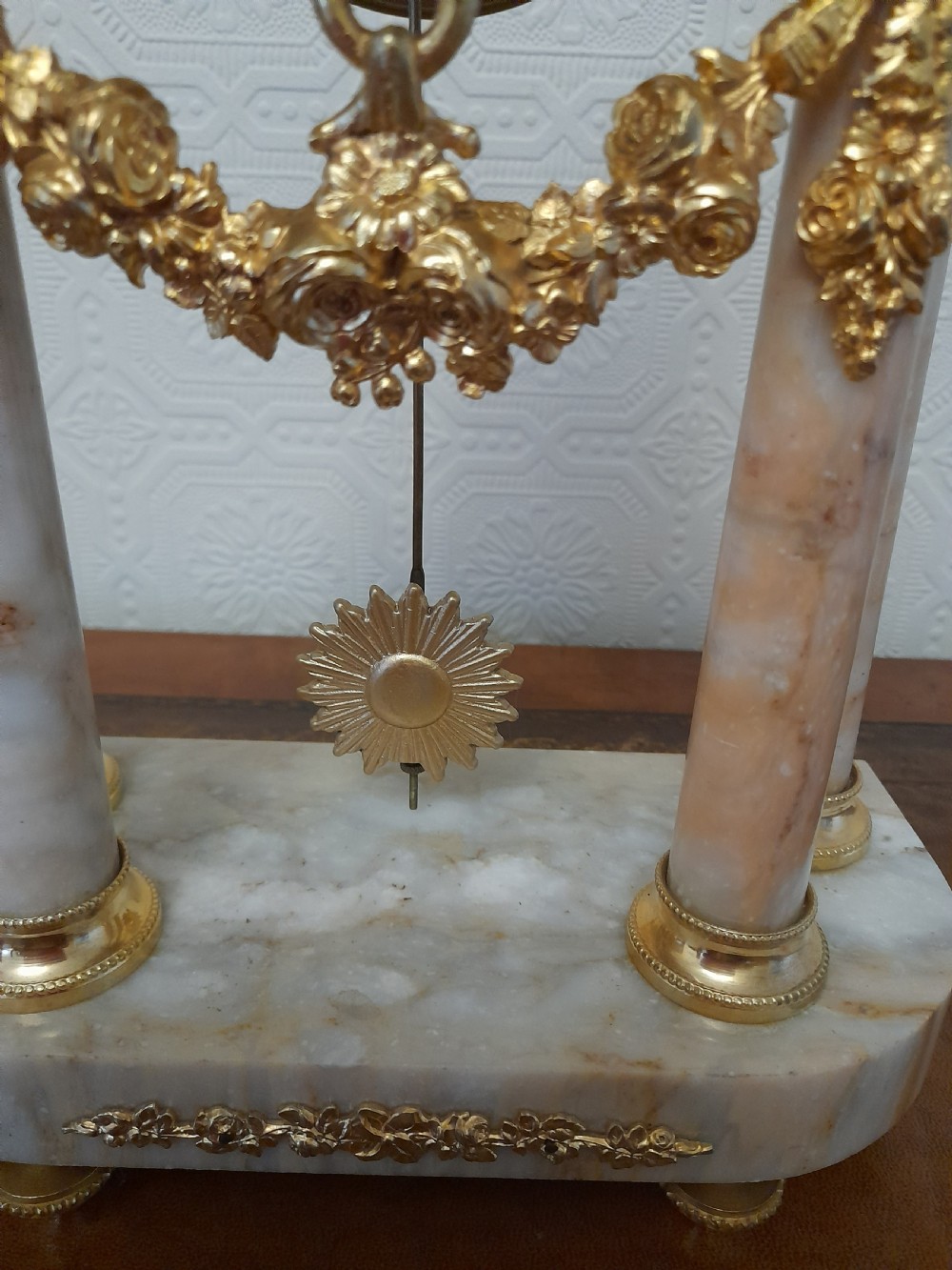 A French Louis XVI style marble and gilt brass portico mantel clock featuring four columns, floral swags, an urn finial, and an enamel dial. View III