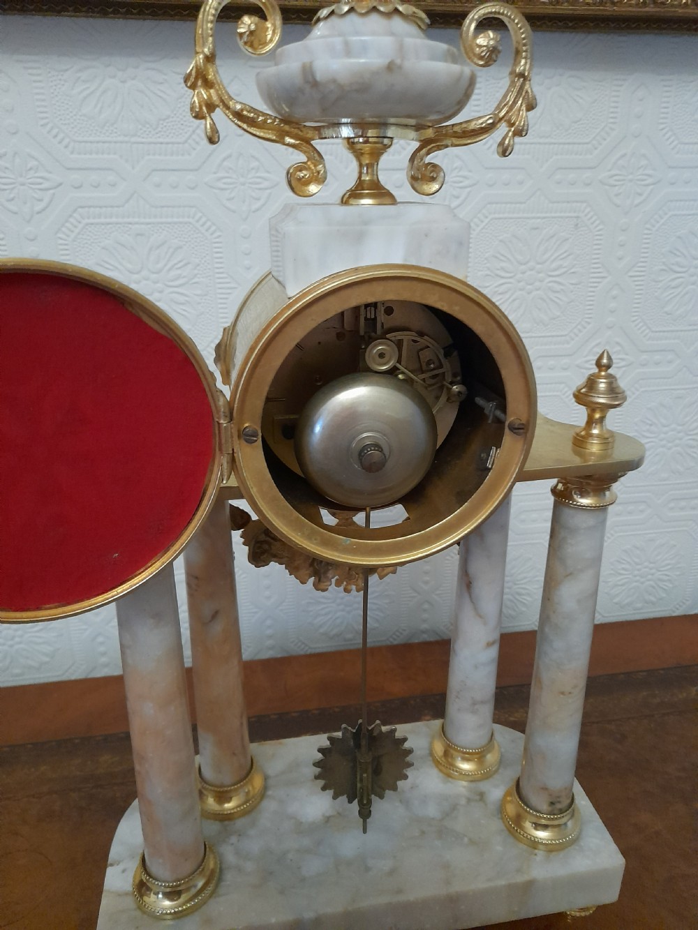 A French Louis XVI style marble and gilt brass portico mantel clock featuring four columns, floral swags, an urn finial, and an enamel dial. View VI