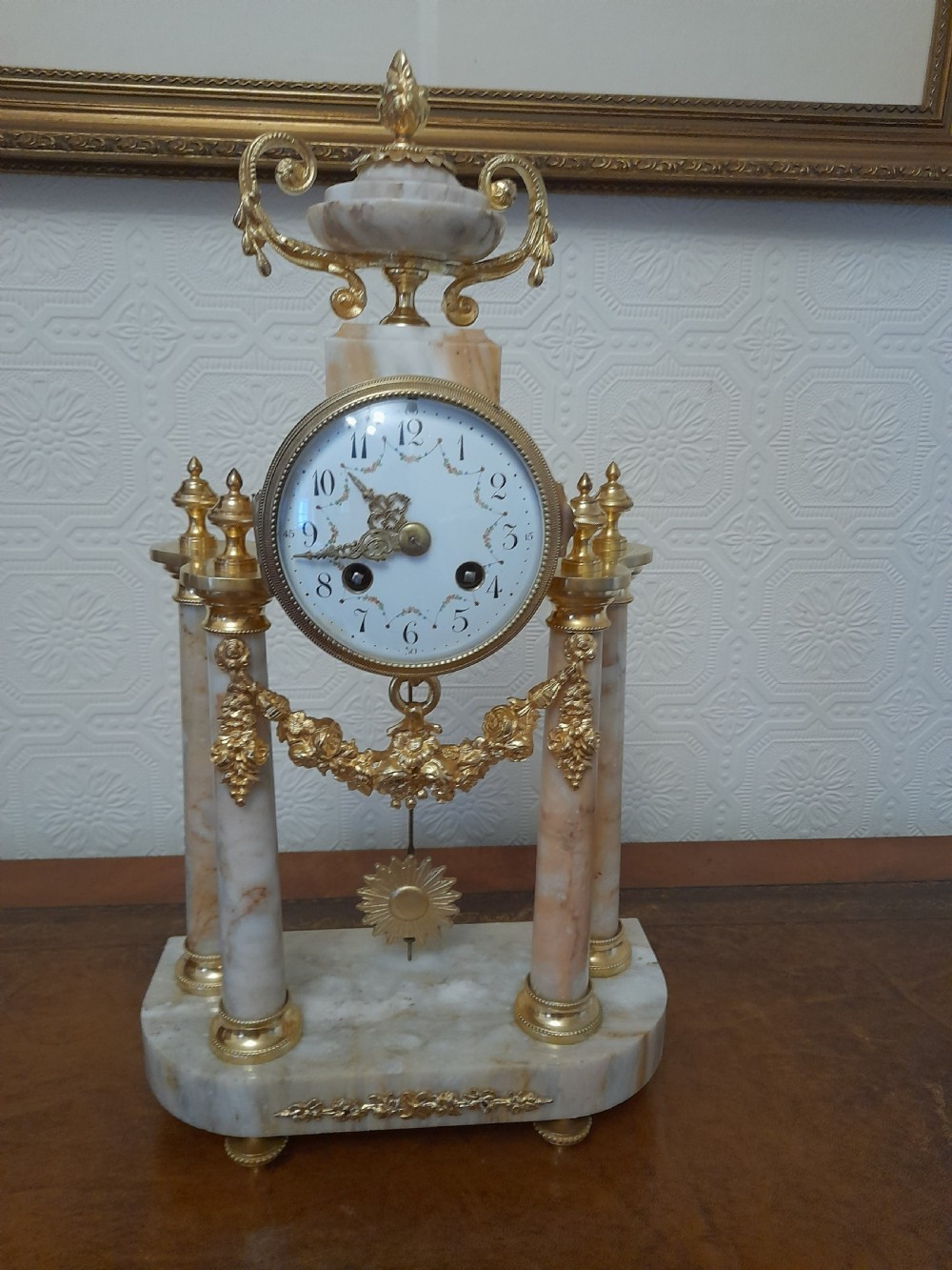 A French Louis XVI style marble and gilt brass portico mantel clock featuring four columns, floral swags, an urn finial, and an enamel dial. View VII