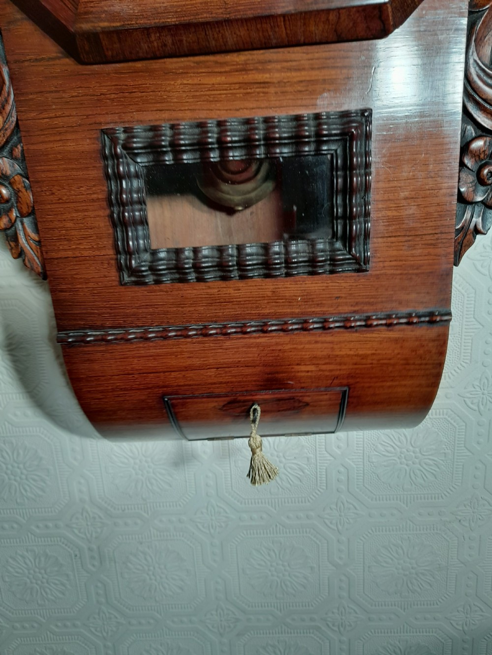 An antique mahogany drop-dial wall clock featuring an octagonal bezel frame, cream dial with Roman numerals, signature Brockbanks London, and carved side scrolls. View III