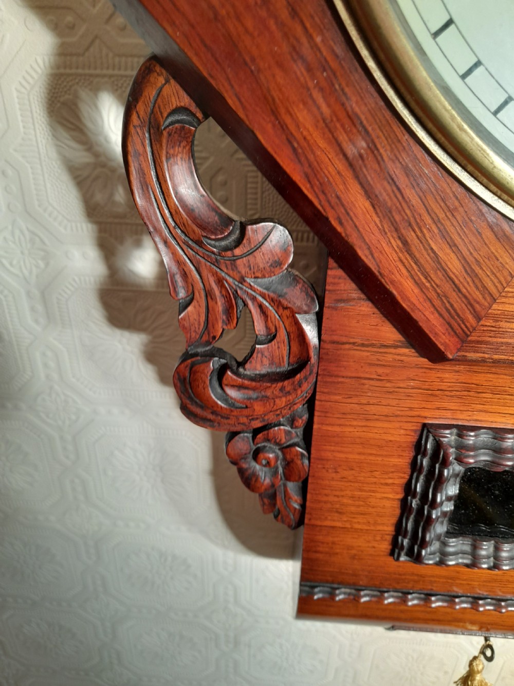 An antique mahogany drop-dial wall clock featuring an octagonal bezel frame, cream dial with Roman numerals, signature Brockbanks London, and carved side scrolls. View V