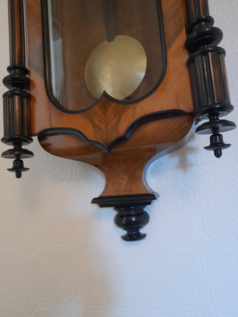 A dark walnut-cased Gustav Becker twin-weight Vienna regulator wall clock featuring turned side columns, carved cresting, twin brass weights, and a white enamel Roman numeral dial. View VII