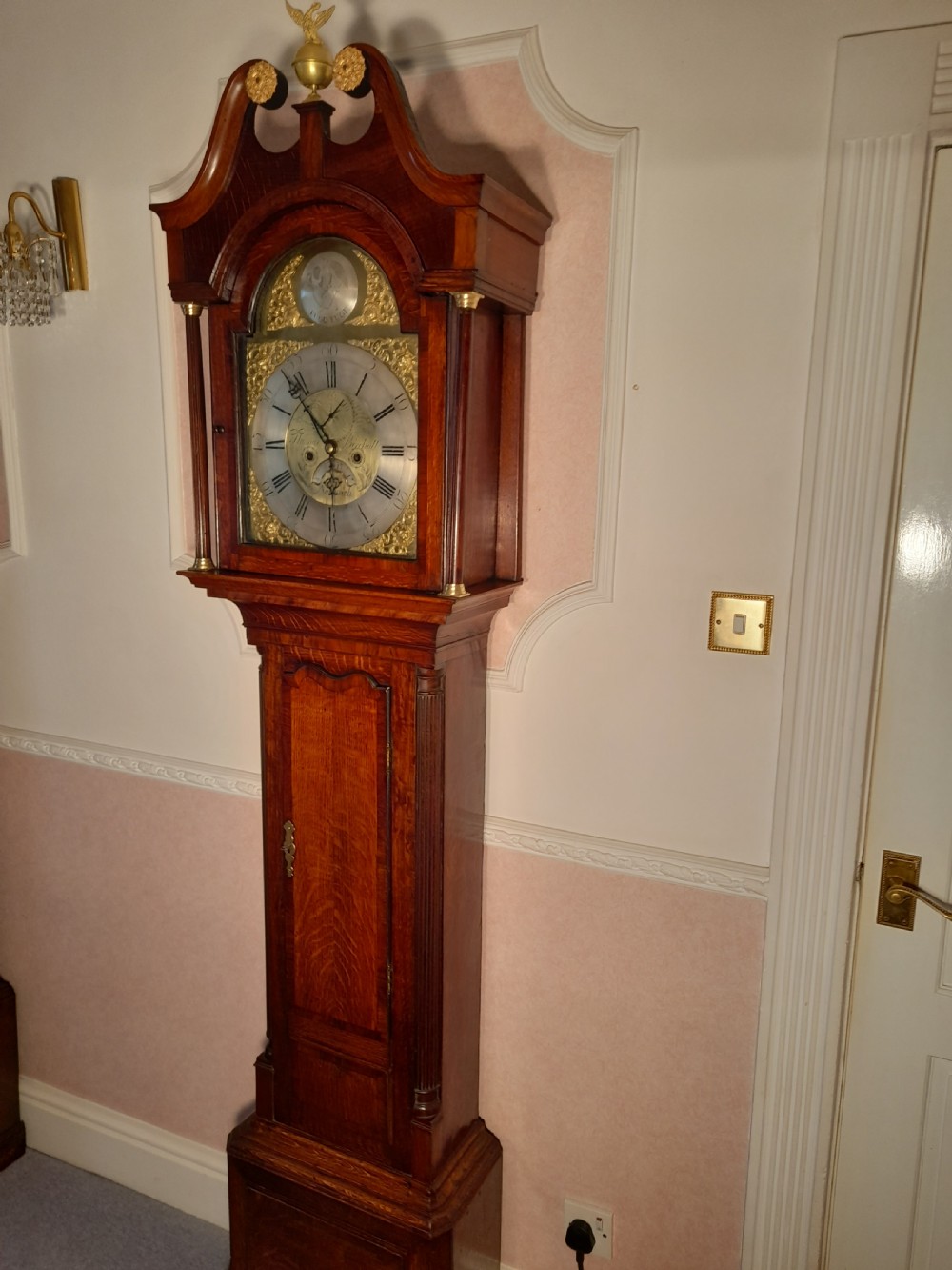 A Georgian mahogany longcase clock featuring a swan-neck pediment with a brass eagle finial and an engraved brass dial.