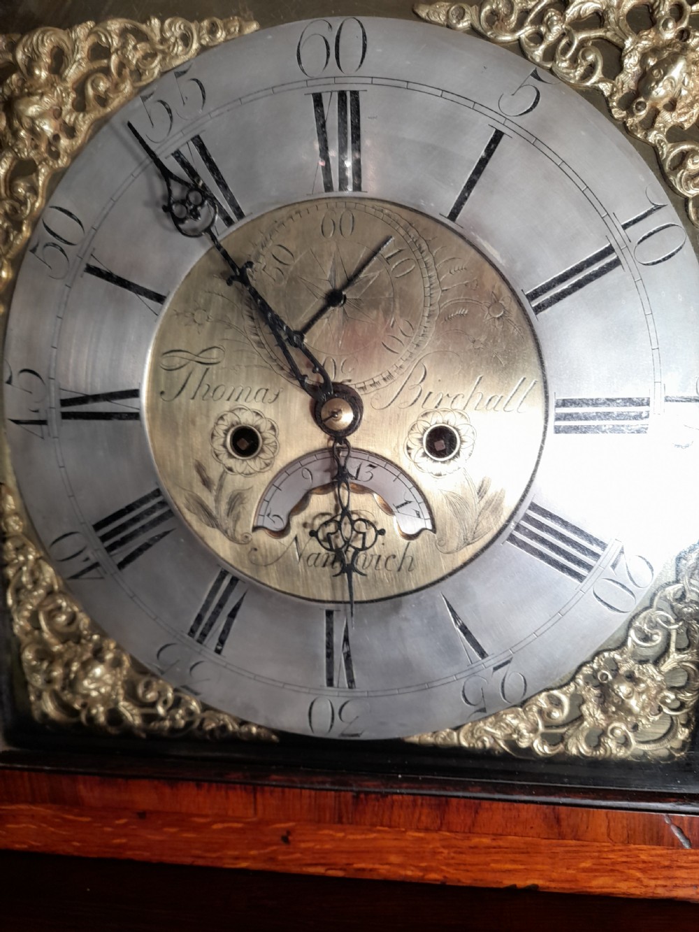 A Georgian mahogany longcase clock featuring a swan-neck pediment with a brass eagle finial and an engraved brass dial. View V