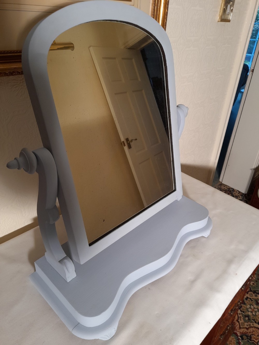 A grey-painted Victorian swing dressing table mirror featuring an arched glass frame set between turned supports on a contoured serpentine base. View II